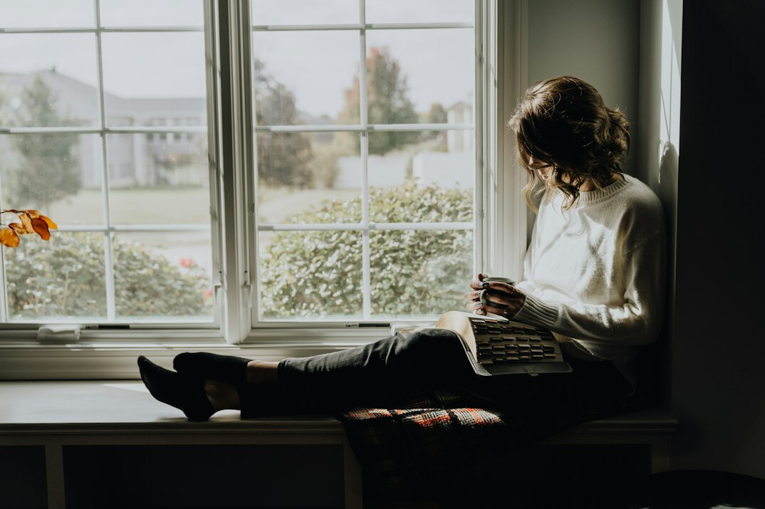 woman reading book by window
